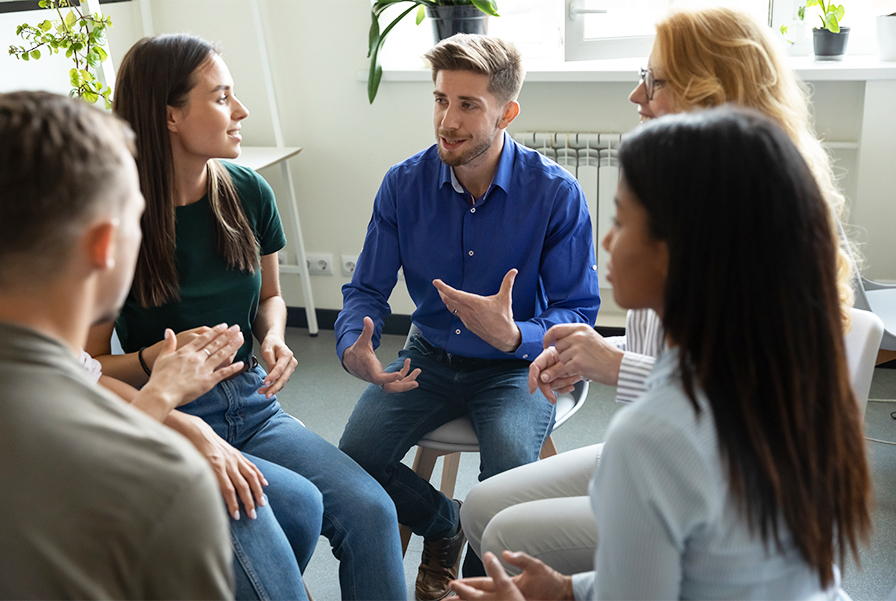 A group of students in a peer support session, discussing mental health and academic burnout.