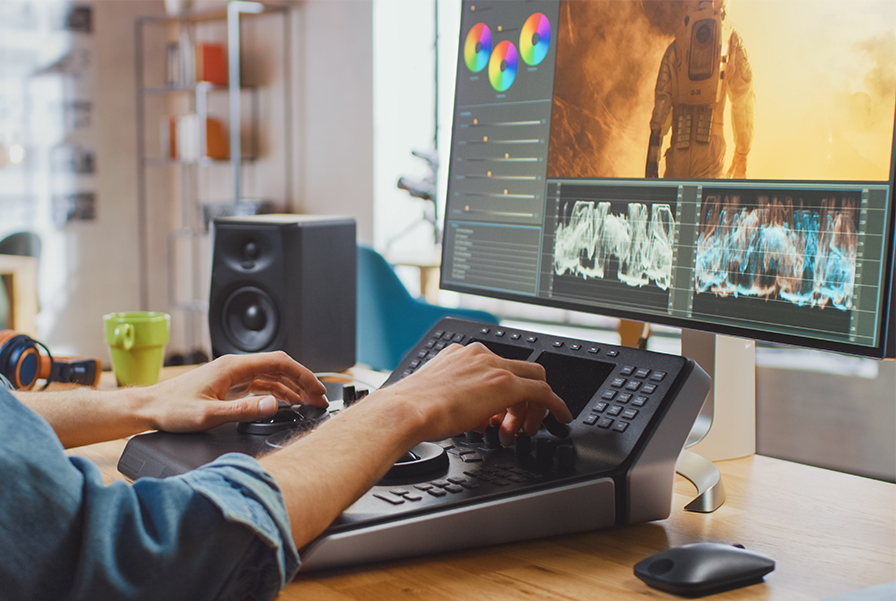 A student in UOW Malaysia's VFX course mastering post-production skills by colour grading a film scene on a professional editing suite.