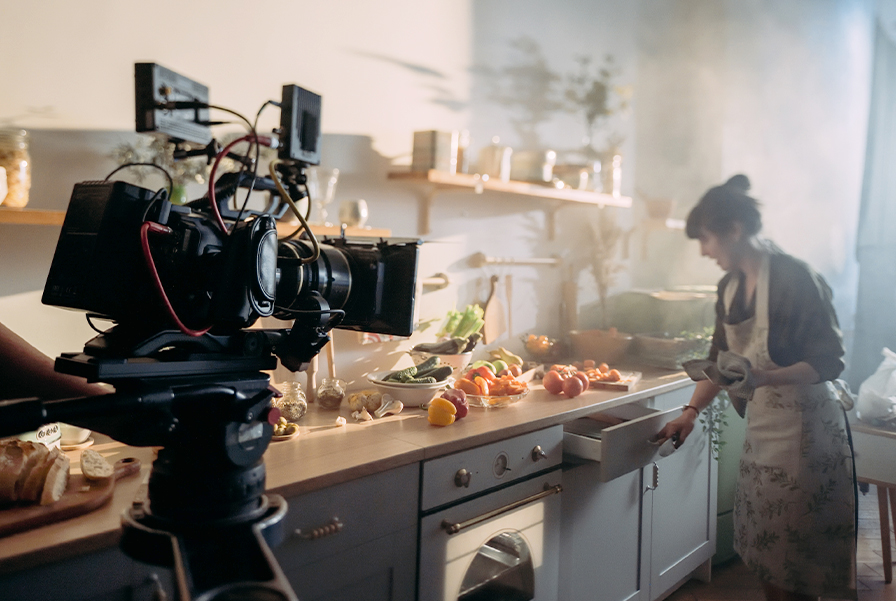 A UOW Malaysia digital media production student gains hands-on film production experience shooting a scene in a kitchen studio with a professional camera.